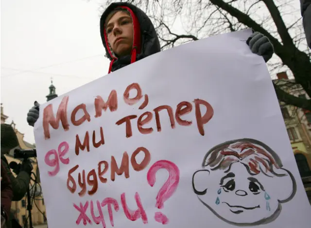 Хлопчик-переселенець тримає плакат на акції переселенців