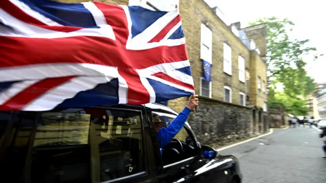 یک راننده تاکسی بعد از اعلام نتیجه انتخابات پرچم بریتانیا را بیرون شیشه خودرو گرفته است