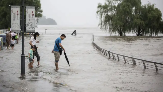 江苏南京民众在泛滥的长江江畔流连（中新社图片2/7/2016）