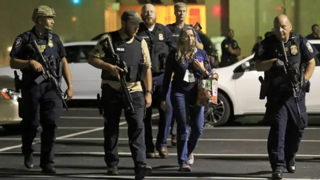 警察护送一名靠近枪击案发生地点的妇女离开现场。