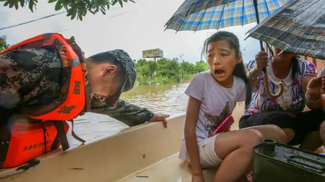 救援人员帮助居民用小船离开水淹区域