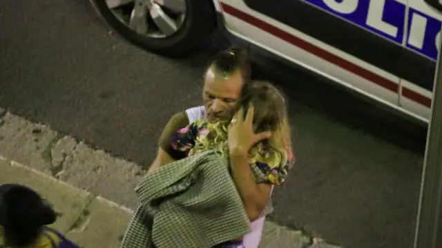 رجل يحمل طفلة أصيبت في الهجوم