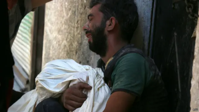 Seorang pria menangisi kematian anaknya setelah serangan pesawat udara di kota Aleppo, Suriah.