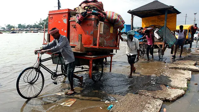 इलाहाबाद में गंगा का पानी बढ़ने के बाद अपना सामान हटाते लोग.