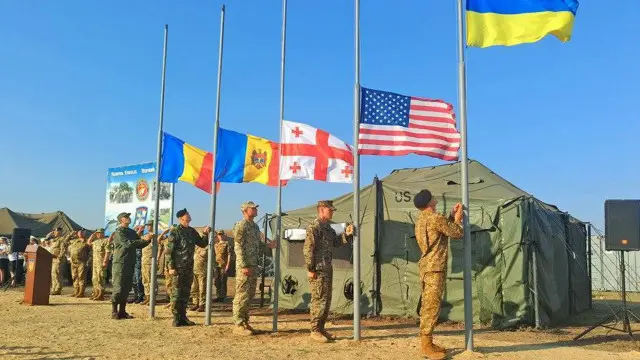 Представники підрозділів морської піхоти піднімають державні прапори у польовому таборі на полігоні Широкий Лан.