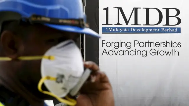 一名建筑工人在1MDB标志前打电话