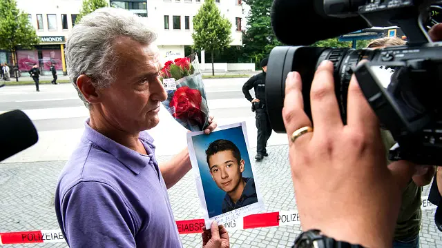 Ayah dari salah satu korban tewas menunjukkan foto anak laki-lakinya, Zabergja Dijamant, dan bunga yang dibawanya. 