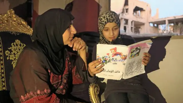 اسلام کتابی را که از کتابخانه آوردهاند برای مادرش میخواند