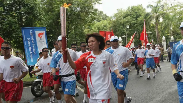 Peraih emas Olimpiade Barcelona 1992, Susi Susanti, membawa obor Olimpiade.