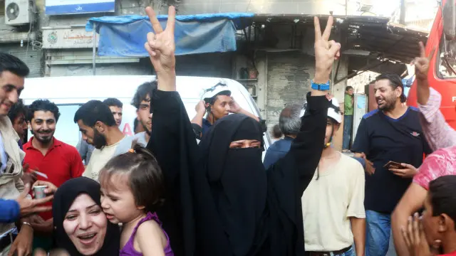 سكان في حلب يرفعون علامة النصر بعد دخول القوات السورية للمناطق التي كان يسيطر عليها مسلحون