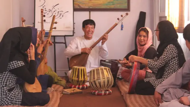 په کانتینر ډوله خونه کې شپږ پیغلې نجونې یوه عمر خوړلي استاد ته ناستې دي چې دخپلې سیمې سوچه موسیقي ور زده کړي