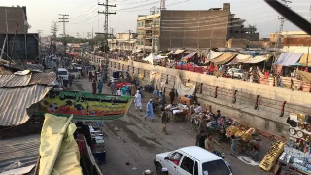 مہاجرین کے سب سے بڑے کیمپ کے ساتھ موجود بورڈ بازار میں افغان تاجر کاروبار کرتے ہیں