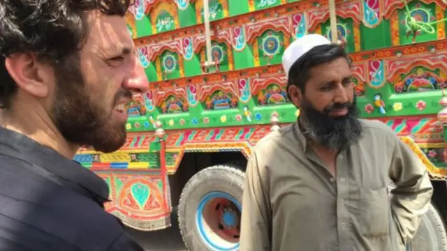 نور محمد (يمين) يقف إلى جوار شاحنة تحمل متعلقاته.