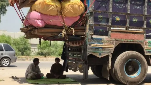 يحتمي الكثيرون من حرارة الشمس تحت الشاحنات.