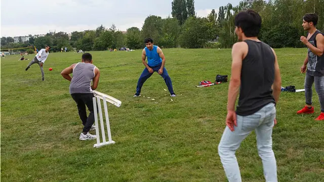 د جرمني برلین کې افغان کډوال عبدالقدیر خان (منځ کې) په ټیمپلهوفر لوبغالي کې له نورو کډوالو سره د کریکټ لوبه کوي. د افغانستان په ګډون د بېلابېلو هېوادونو ګڼ کډوال تېر کال جرمني ته ورسېدل. کریکټ افغانستان کې اوس ښه وده کړې او مشهوره لوبه ده. 