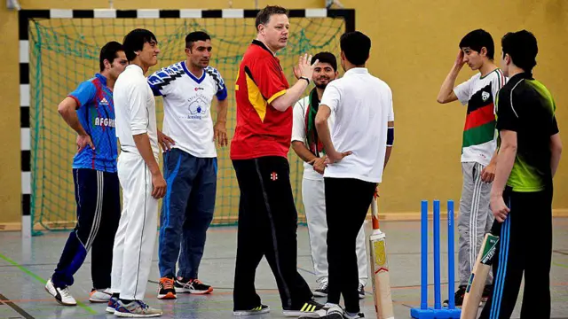 د جرمني د کریکټ بورډ مشر برېن منټل او الټینډورف ۰۹ ابي پړانګانو لوبډلې غړي له افغان کډوالو سره د کریکټ روزنځي کې. 