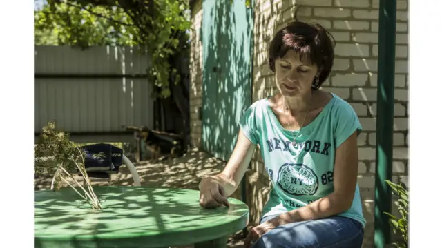 Тетяна сидить біля свого будинку під виноградником, який виростив її чоловік Юрій, що зник безвісти восени 2014 року. Він служив у міліції і був шахтарем. 