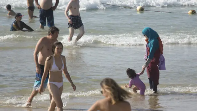 امرأة مسلمة ترتدي زيا محتشما مع طفلها على أحد شواطئ تل أبيب