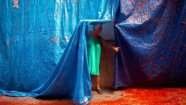 سيدة من سكان بونول بالقرب من مدينة فالنسيا الإسبانية ترفع ستارا واقيا أثناء مهرجان الطماطم الذي يُقام سنويا في إسبانيا. واستخدم المشاركون حوالي 160 طن من الطماطم الناضجة. وكان 22 ألف شخص شاركوا في معركة طاحنة من التراشق بثمار الطماطم على مدار ساعة كاملة. وفكرة المهرجان مستوحاة من تراشق الأطفال المحليين في المدينة بالطعام عام 1945.