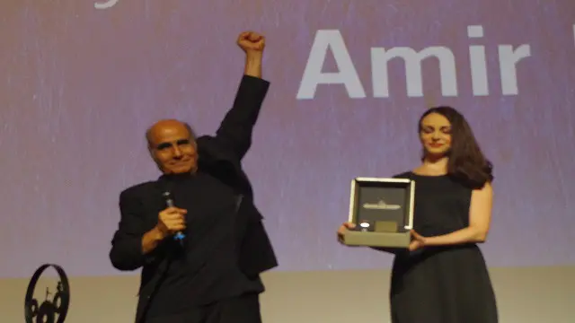 أمير نادري المخرج الإيراني يرفع يده في إشارة إلى الصمود