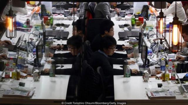 在北京联合创业空间科技寺里工作的员工，他们的身影反射在玻璃门上(图片来源：TomohiroOhsumi/Bloomberg/Getty Images)