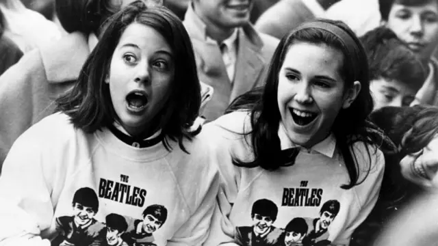 紐約甲殼蟲樂隊眾多狂熱的粉絲中,兩名身著甲殼蟲樂隊汗衫、激動萬分的女孩,她們是來機場歡迎偶像的到來。(圖片來源:Getty Images)