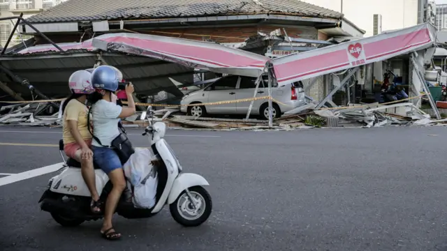 高雄過路民眾朝著一家便利店倒塌的簷蓬拍照（15/9/2016）