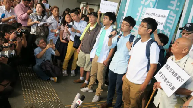 Joshua Wong (người thứ ba đeo kính, mặc áo trắng trong ba thanh niên giữa hình) sẽ làm chân phụ thủ thư ở thư viện