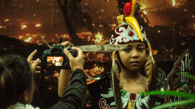 Seorang anak berpakaian adat Dayak tengah berkunjung ke pameran foto "I am the forest" di dekat Palangkaraya.