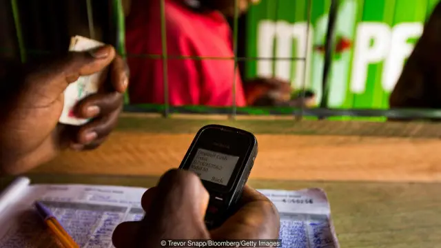 Một nhân viên tại cửa hang M-Pesa ở Nairobi, Kenya, nơi dịch vụ thanh toán bằng dịch vụ di động nay được áp dụng trong hàng triệu giao dịch (Hình: Trevor Snapp/Bloomberg/Getty Images)