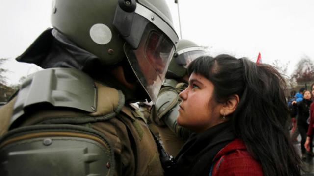 在智利首都圣地亚哥纪念1973年政变的游行示威中，一名示威者用双眼紧盯着防暴警察。(图片来源: Carlos Vera/Reuters)