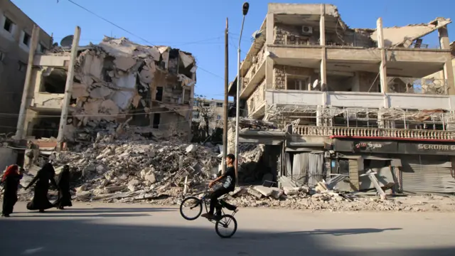 阿勒颇一座被炸毁楼房前一名男孩在玩自行车（6/10/2016）