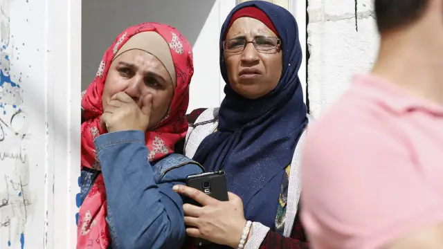 فلسطينيتان من سكان القدس الشرقية تتراقبان إجراءات الشرطة الإسرائيلية لتأمين مكان الهجوم. 