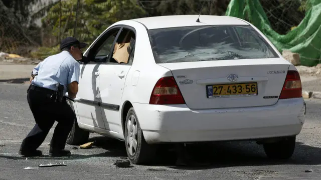 ضابط إسرائيلي يفحص السيارة التي تقول الشرطة إن المهاجم استخدمها في تنفيذ الهجوم.