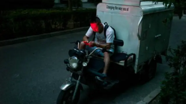 北京的一位外卖送餐员正在查看自己的手机(图片来源:Getty Images)