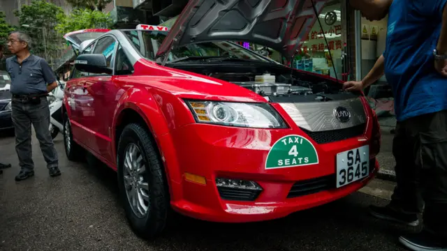 香港一群出租车司机在端详一辆比亚迪电动出租车(资料图片)