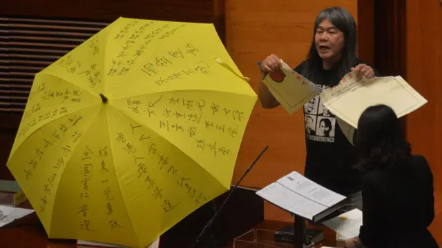 绰号“长毛”的议员梁国雄在宣誓现场撕毁印有中国人大831决议的纸张。