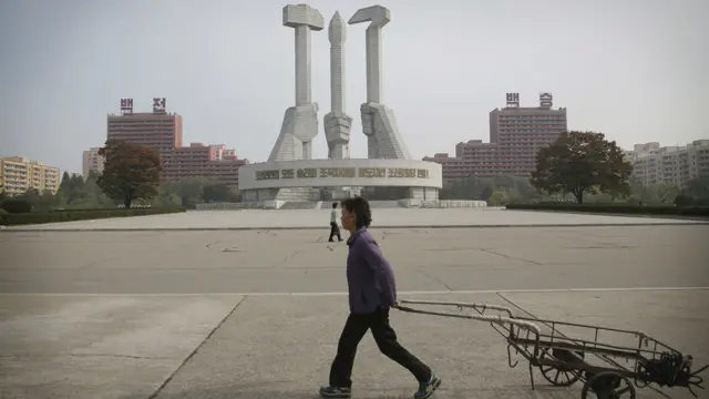 一名女子拉着小车通过平壤一座纪念碑（15/10/2016）