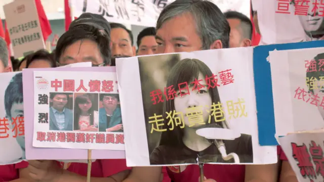 在香港立法会外,示威者手持标语牌抗议“青年新政”的梁颂恒、游蕙祯上周宣誓时“辱华”。