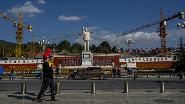 一个父亲背着小孩走在东方红广场上