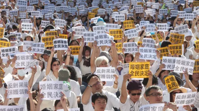 下一代幸福联盟号召反对同性婚姻合法化的民众身穿象征“光明正面诉求”的白衣，手持大会发放的标语表达抗议。 