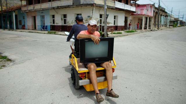 мужчина эвакуирует телевизор перед ураганом