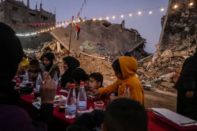 فلسطينيون يتناولون الطعام أمام طاولة ممتدة في شوارع غزة 