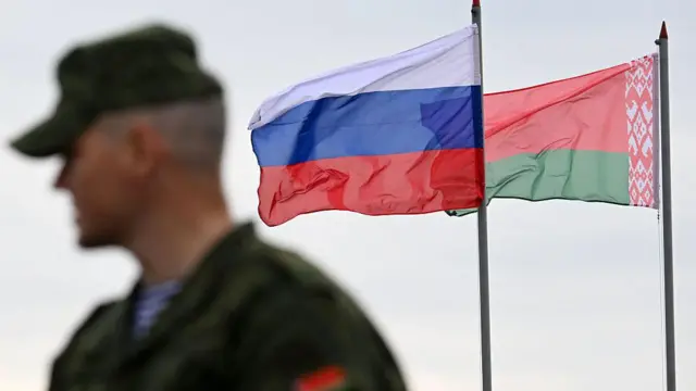 Военный на фоне российского и белорусского флагов 