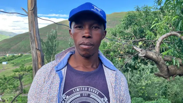 Une photo de la tête et des épaules de Thabiso, le jeune frère de Tiger. Il se tient devant des collines verdoyantes.