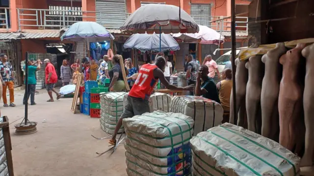 Nwoke yi uwe mme mme na-akpọsa ngwaahịa ya n'ụlọahịa ya dị n'Onitsha Main Market.