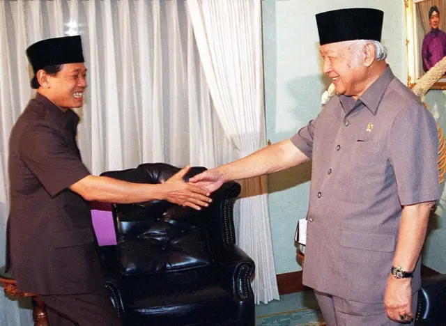 Presiden Indonesia Suharto (kanan) menyambut Ketua DPR Harmoko (kiri) 16 Mei di kediaman presiden Cendana di Jakarta. Soeharto akan melakukan perombakan kabinetnya, Harmoko mengumumkan setelah pertemuan, karena itu adalah salah satu aspirasi rakyat yang telah disampaikan ke parlemen dan Soeharto telah menyetujuinya.
