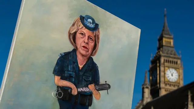 Плакат с Терезой Мэй в военной форме на фоне парламента