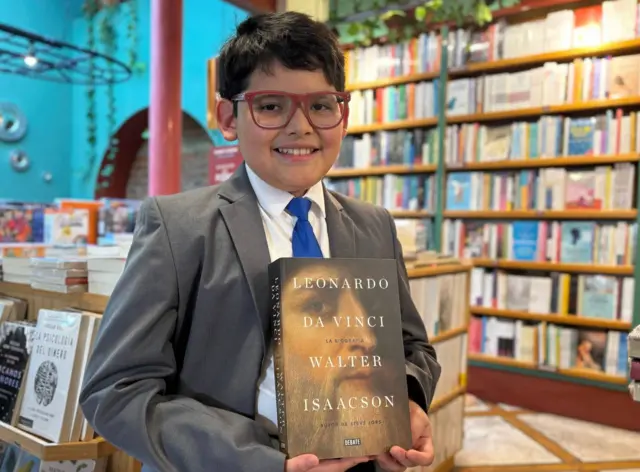 David Camacho sostiene un libro sobre Leonardo da Vinci con la foto del genio renacentista en la carátula.