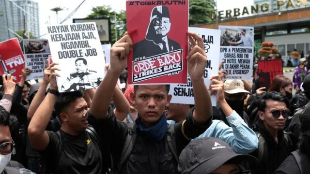 Indonesian activists hold placards during a protest against the revision of the country's military law in front of the Parliament building in Jakarta on 20 March